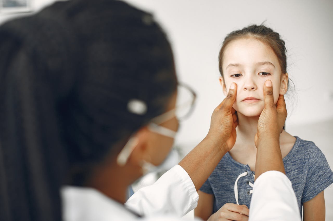 A female doctor carefully examines a young girl