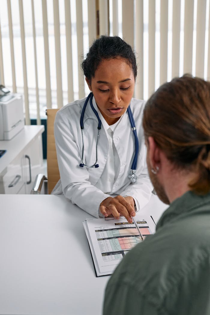 Female doctor discusses health chart with patient during consultation in office setting.