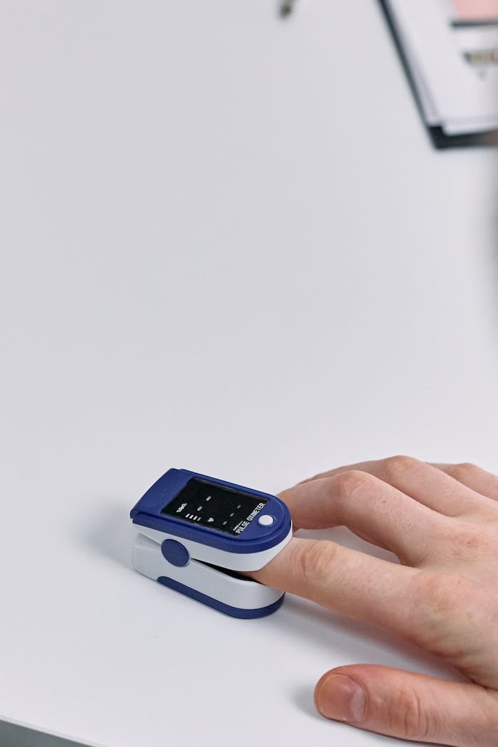 Offerings Close-up of a hand using a pulse oximeter on a white table, displaying health data.